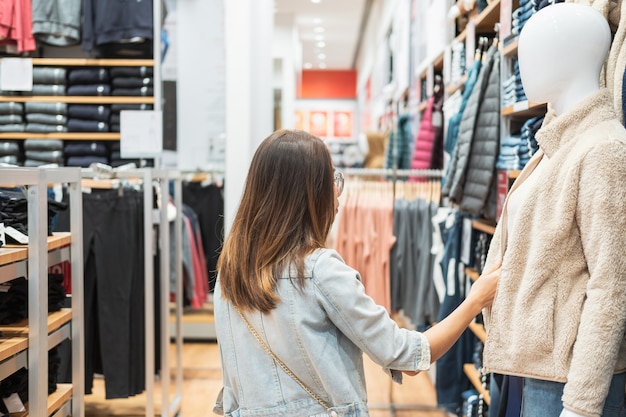 Young asian woman choosing clothes in clothing store at the mall