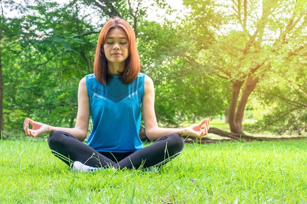 Молодая женщина Азии закрыть глаза и практикующих сидеть йога на открытом воздухе природа фон