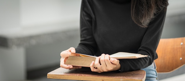 A young Asian woman college student wears a medical face mask with a school backpack to protect from influenza virus COVID-19 pandemic while studying in college building campus. Education stock photo