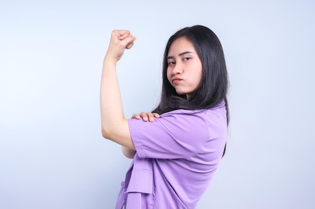 Foto giovane donna asiatica sicura e orgogliosa che mostra i suoi muscoli forti sente il suo successo un risultato