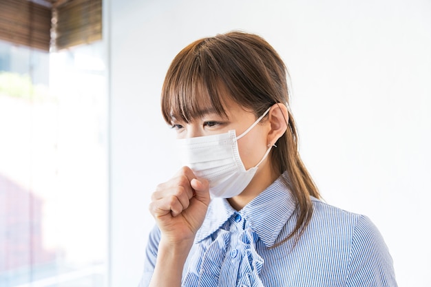 Young Asian woman coughing with one hand on mouth