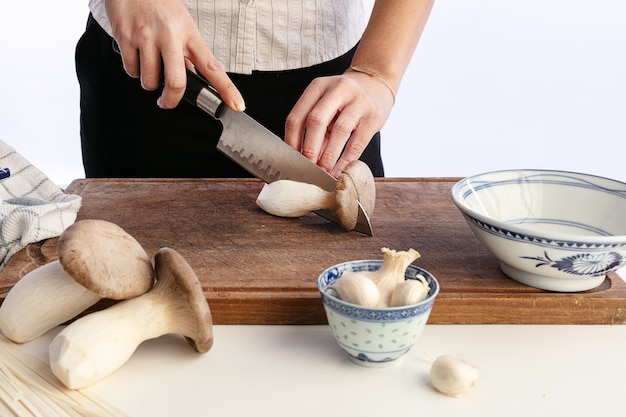 Young Asian woman cutting mushrooms