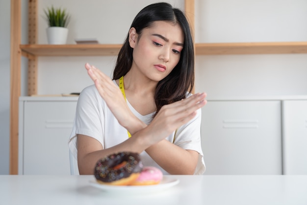 Young Asian woman on dieting refuses donuts junk food .Dieting and good health concept