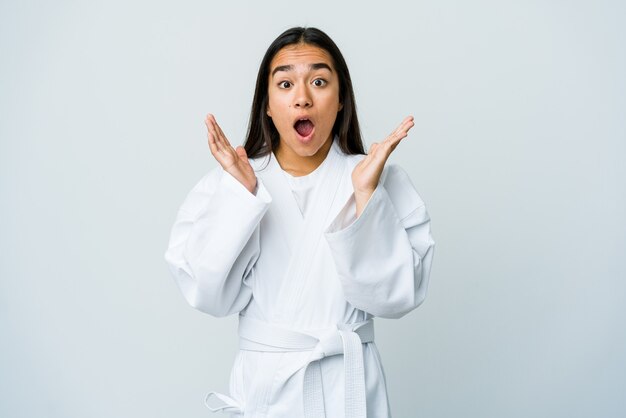 Young asian woman doing karate isolated on white wall surprised and shocked.