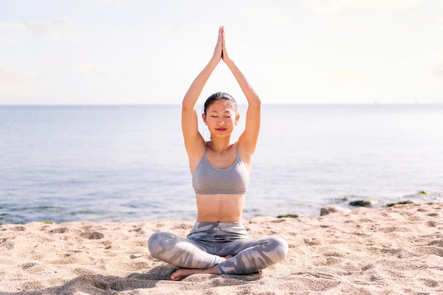 Photo young asian woman doing yoga exercises at beach