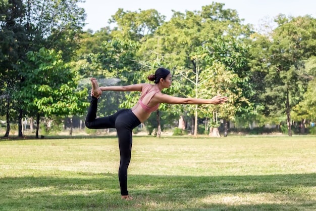 Foto giovane donna asiatica che fa yoga al mattino al parco