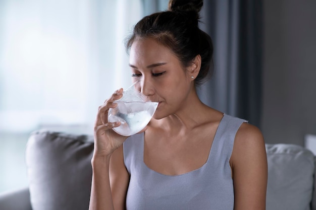 写真 ガラスから氷で純粋な水を飲む若いアジアの女性水ガラスから飲む女性ヘルスケアの概念