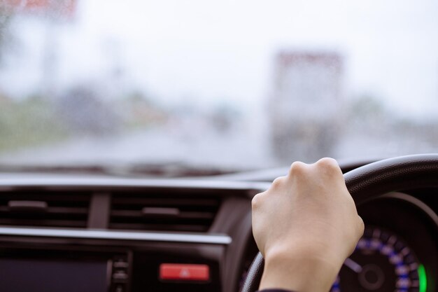 Young asian woman driving a car while the rain carefully woman\
pay an attention on the road during driving a car in the rain\
safety and responsibility transportation concept