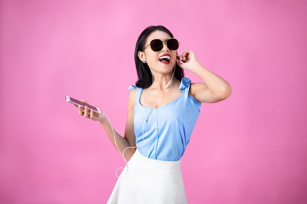 Young asian woman in earphones listening to music and dancing