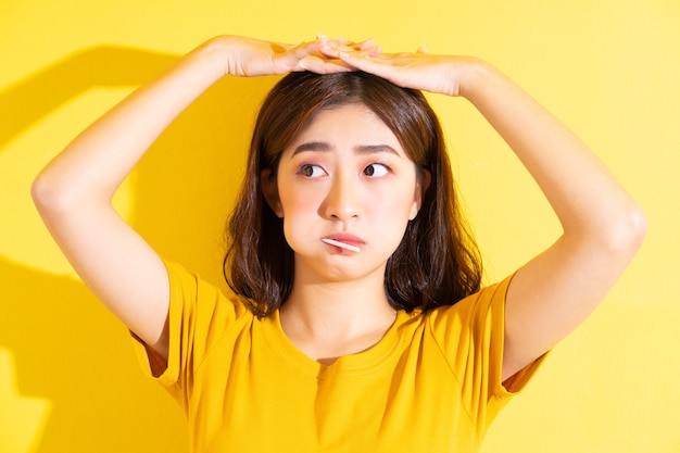 黄色のロリポップを食べる若いアジアの女性