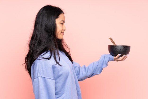 Young asian woman eating noodles isolated