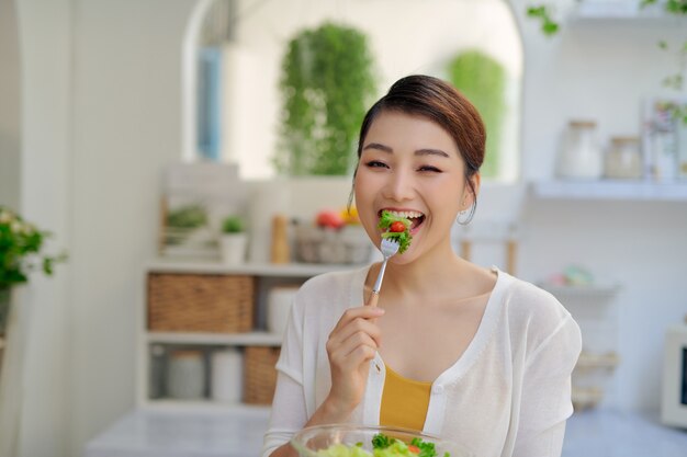 Giovane donna asiatica che mangia la verdura dell'insalata nel concetto di dieta