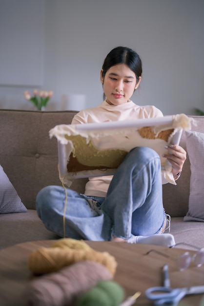 アジアの若い女性は,趣味のライフスタイルで手作りの工芸のためにパンチ針で布に刺<unk>糸を刺します.