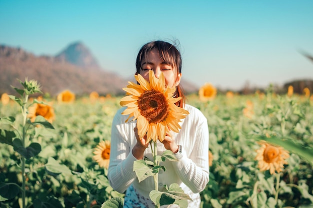 Young asian woman enjoying nature on the field of sunflowers at sunset