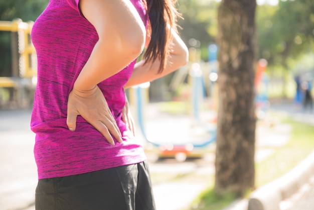 Young asian woman feel pain on her back and hip while exercising