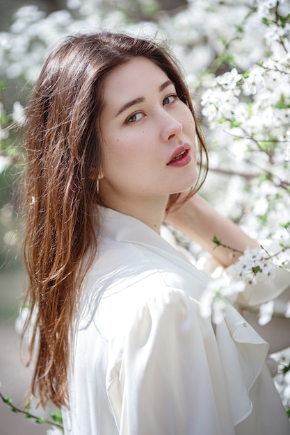 Young asian woman in a flowering garden. romantic image of stylish casual woman , trendy silk blouse. positive mood. Cheery Blossom full bloom in Japan.