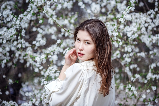 Young asian woman in a flowering garden. romantic image of stylish casual woman , trendy silk blouse. positive mood. Cheery Blossom full bloom in Japan.