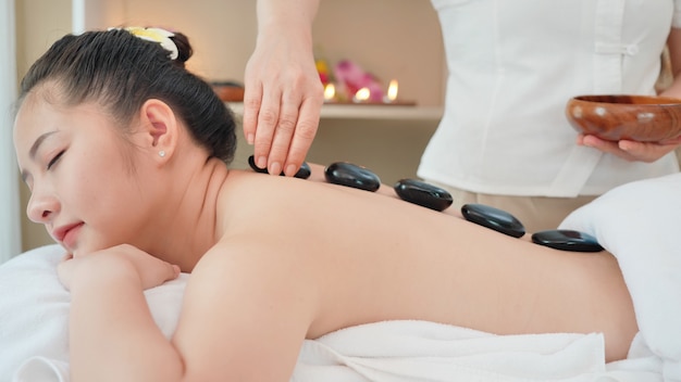 Photo young asian woman getting spa massage with hot stone massage at beauty spa salon. relaxing massage for health