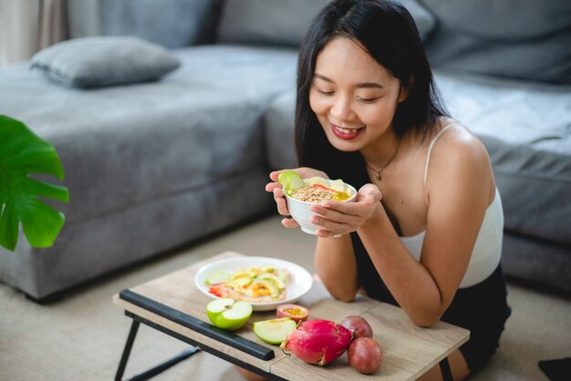 Giovane donna asiatica ragazza che tiene cibo salutare verdura fresca nello stile di vita a casa, donna bella persona vegetariana che fa nutrimento dietetico mangia insalata, la gente sorride felice, concetto di cibo sano