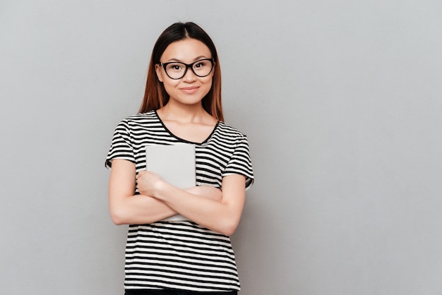 Young asian woman in glasses holding book