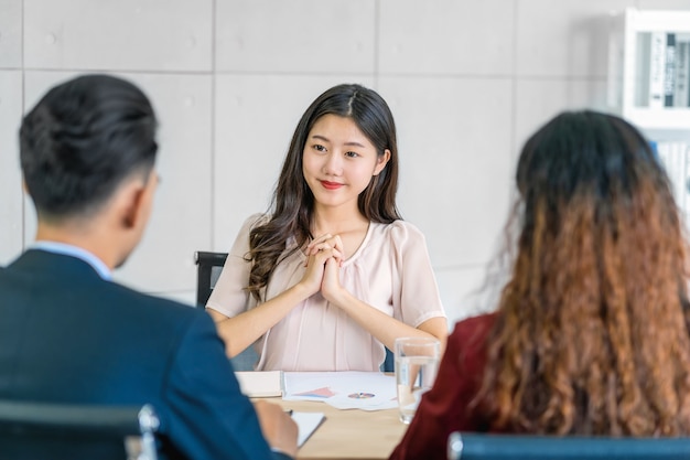 사진 긍정적인 움직임으로 두 명의 관리자와 인터뷰하는 젊은 아시아 여성 졸업생