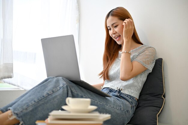 Young Asian woman having an online meeting or video calling with her friends through laptop