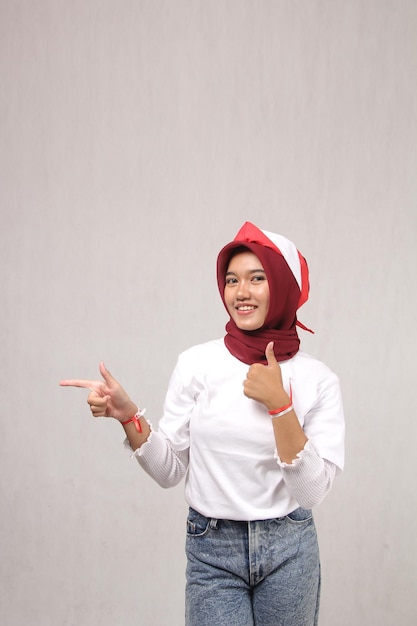 young asian woman in hijab wearing stylish white tshirt with finger pointing empty space