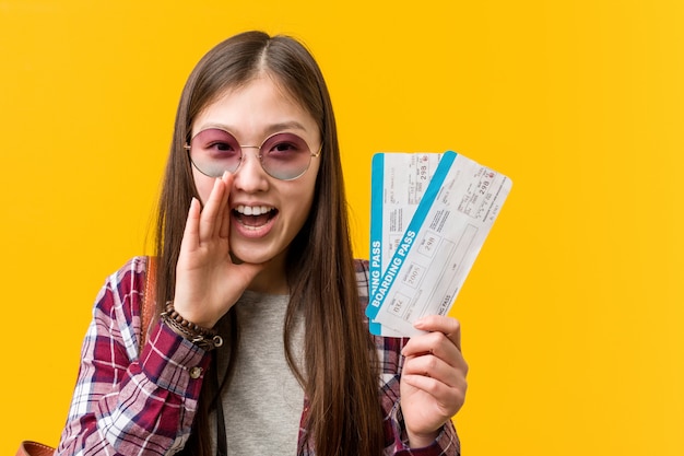 Young asian woman holding an air tickets shouting excited to front