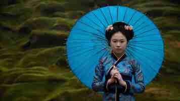 Photo young asian woman holding blue umbella standing isolated on green background