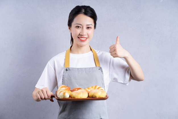 배경에 빵을 들고 젊은 아시아 여자