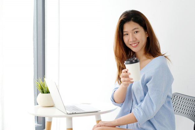 Young asian woman holding a coffee cup with smiling face