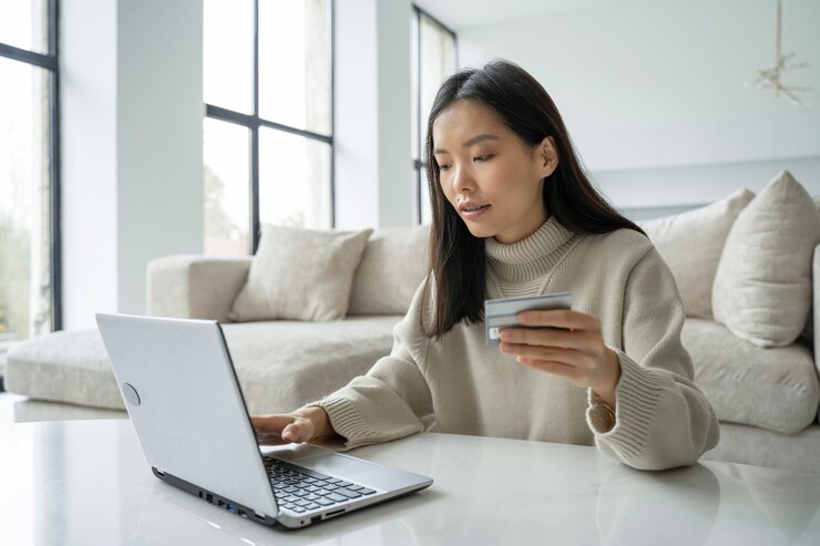 Photo クレジットカードを保持し、ラップトップを使用して自宅で働く女性起業家の若いアジア人女性