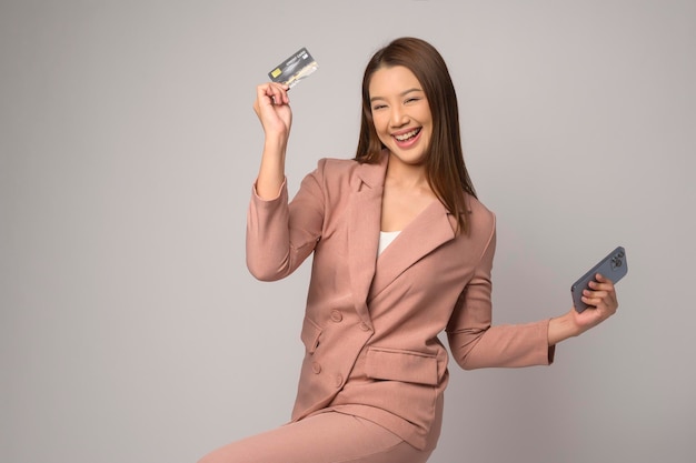 Young asian woman holding credit card over white background studio shopping and finance concept