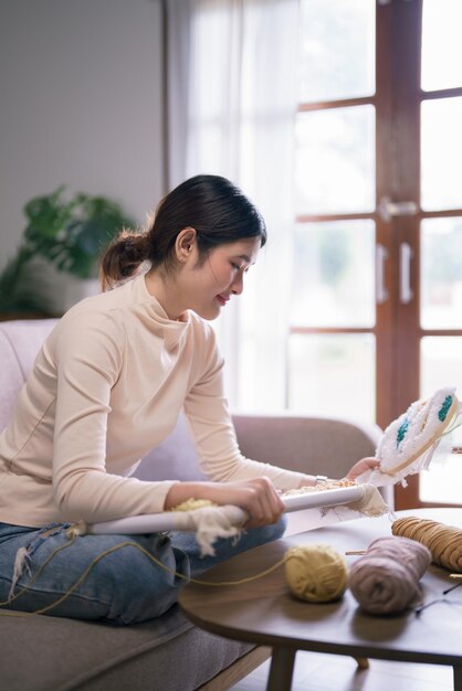 young asian woman holding embroidery fabric frame with punch needle technique in hobby lifestyle