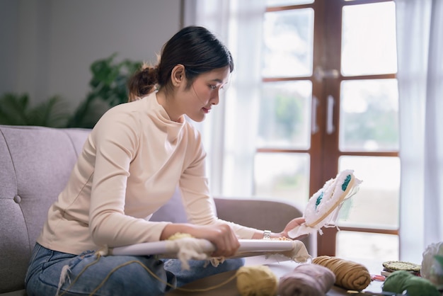 young asian woman holding embroidery fabric frame with punch needle technique in hobby lifestyle