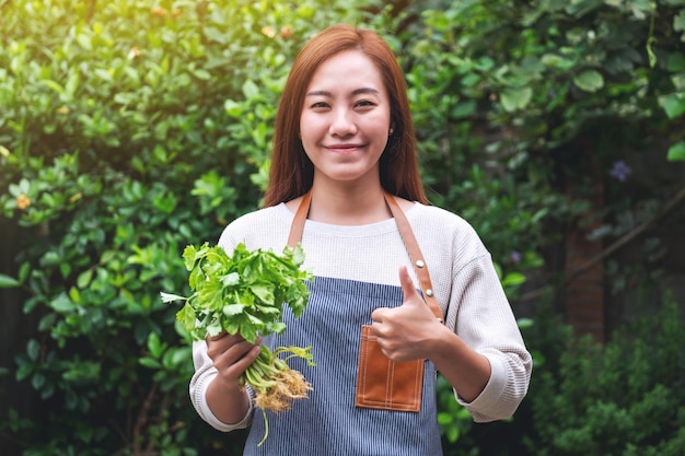 A young asian woman holding and making thumb up to show good sign to celery