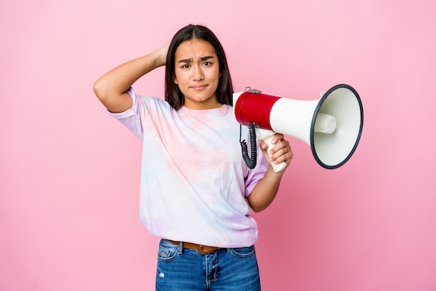 Young asian woman holding a megaphone isolated on pink wall being shocked, she has remembered important meeting.