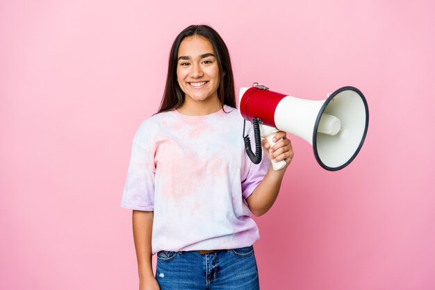 Young asian woman holding a megaphone isolated on pink wall happy, smiling and cheerful.