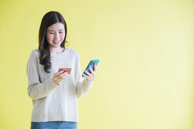 Young asian woman holding mobile phone and credit card for shopping online