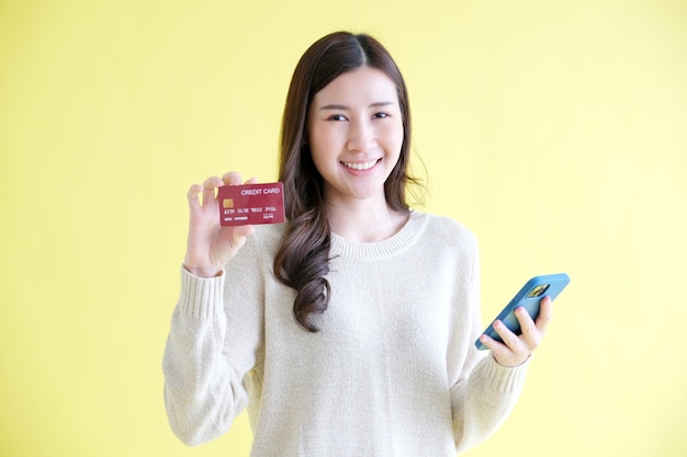 Young asian woman holding mobile phone and credit card for shopping online