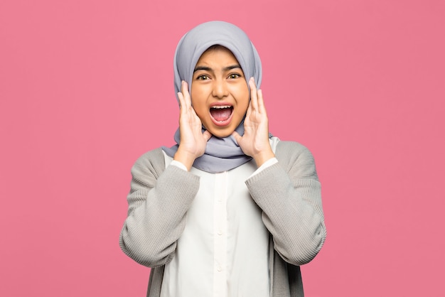 Young Asian woman holding palms on her face and looking amazedly