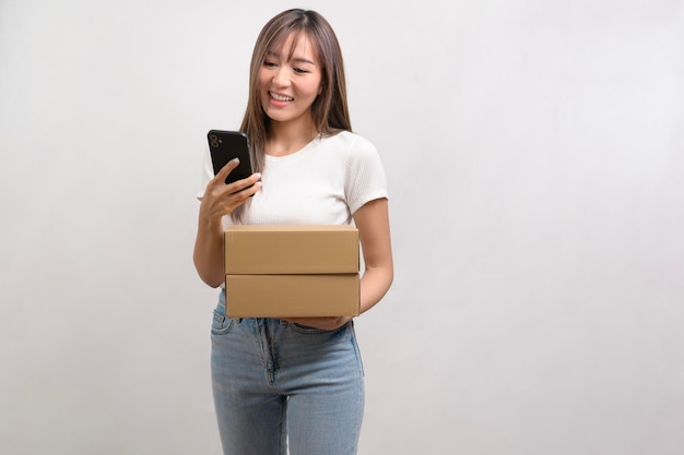 흰색 배경 위에 종이 상자와 카드보드 상자를 들고 있는 젊은 아시아 여성