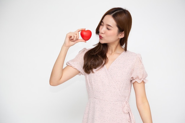 Foto giovane donna asiatica che tiene cuore rosso isolato su sfondo bianco