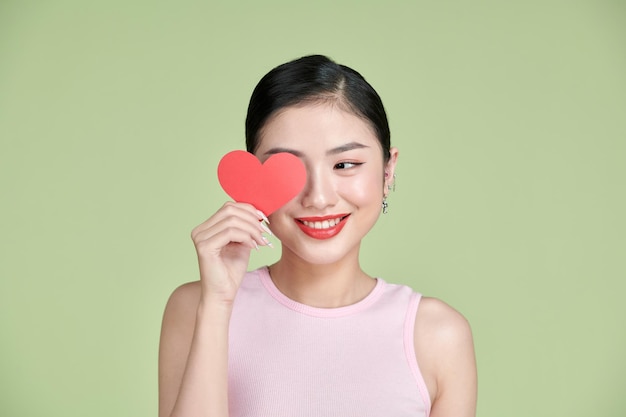 Young asian woman holding a red heart symbol