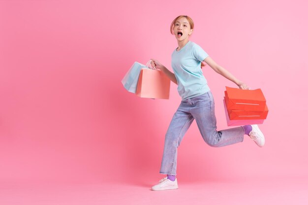 Young Asian woman holding shopping bag on pink background