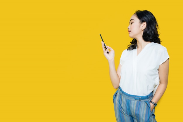 Молодая азиатская женщина держа smartphone