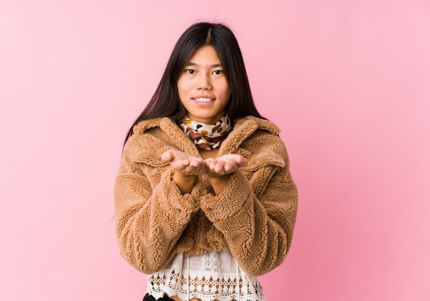 Young asian woman holding something with palms