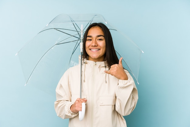 Young asian woman holding a umbrella showing a mobile phone call gesture with fingers.