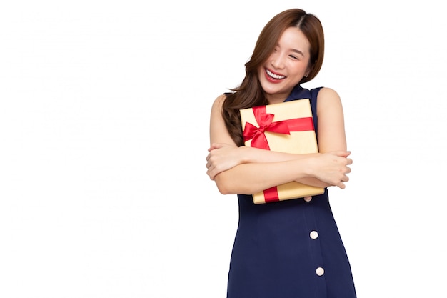 흰색 배경 위에 절연 골드 선물 상자를 포옹하는 젊은 아시아 여성