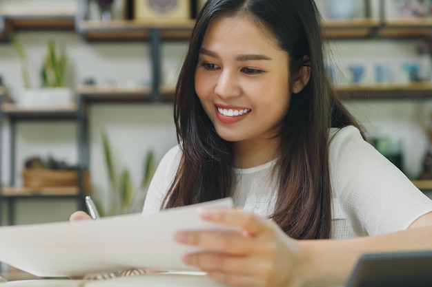 写真 ホーム オフィスで働くスマート カジュアルな服装の若いアジア女性。